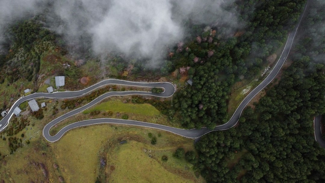 A winding mountain road seen from above, representing unexpected turns in travel